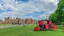 View of a red carriage and Hampton Court Palace